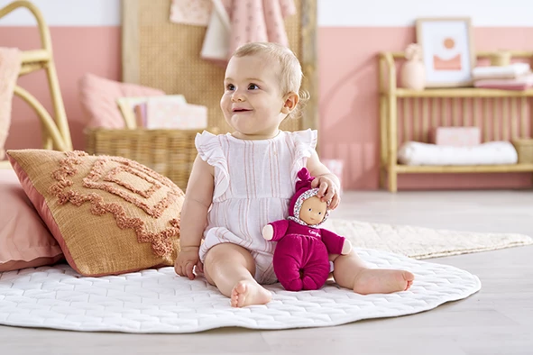 Bébé qui regarde sur le côté en tenant Doudou Babidoux Rose Grenadine